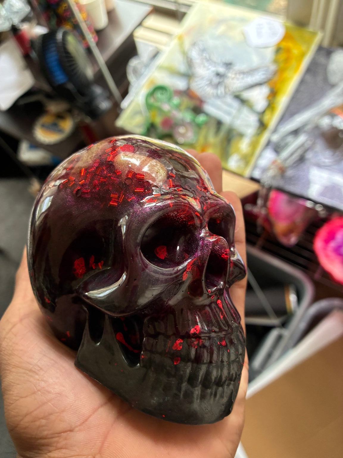 Handmade bloody purple and black epoxy resin skull with red glitter, angled front view