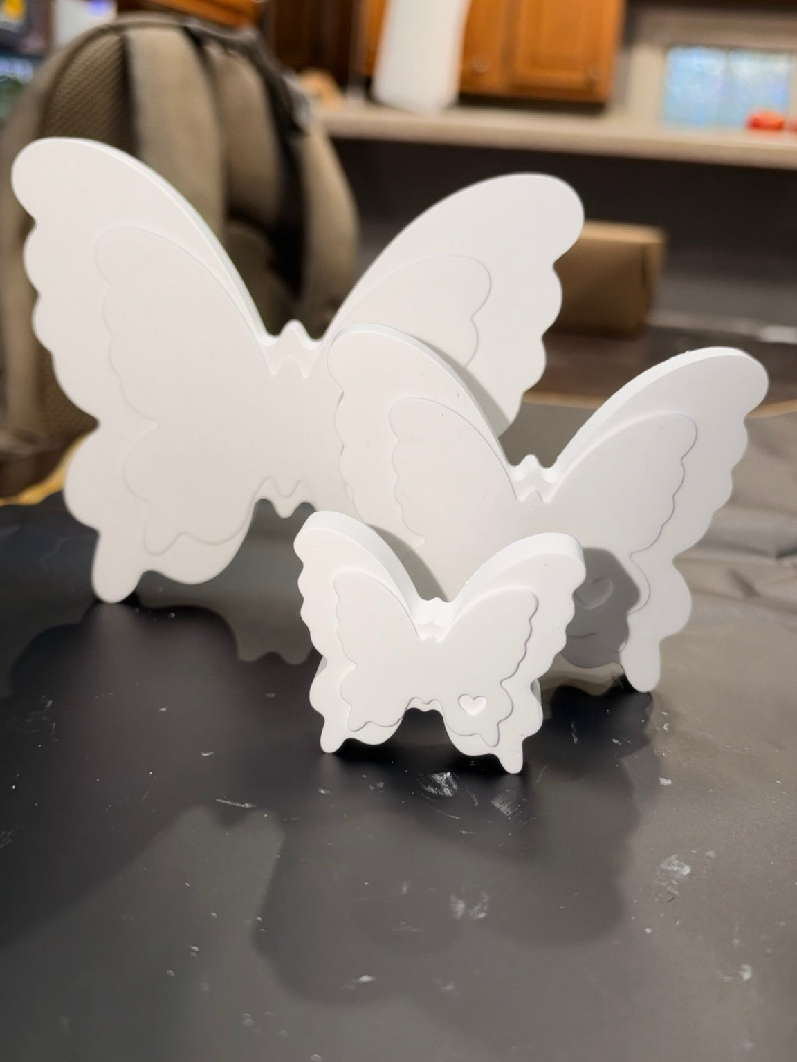 Three white ceramic resin butterfly pieces standing upright in different sizes