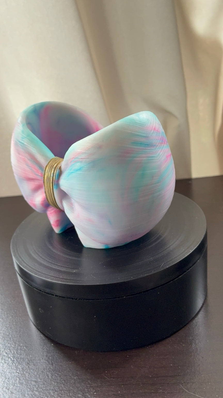 Front angled view of pastel blue pink and white resin bow holder with gold center