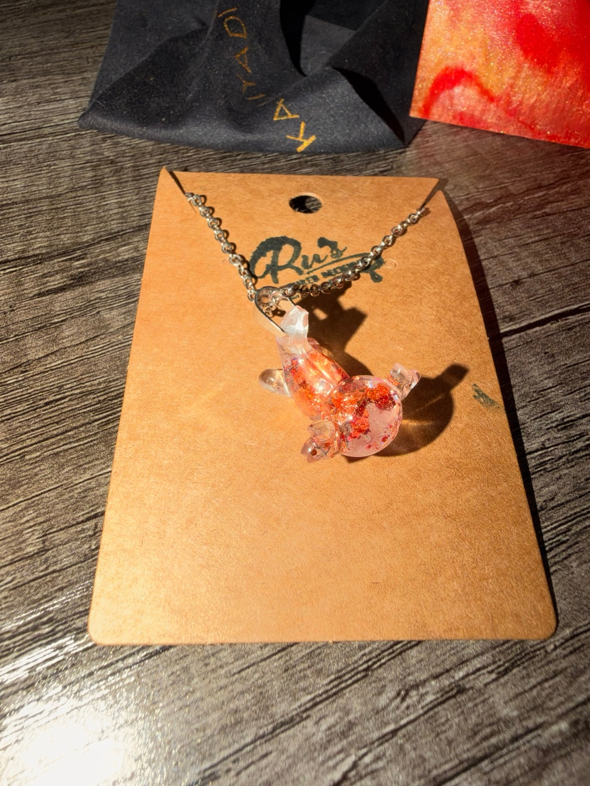 Mini axolotl UV resin necklace on Ru's Poured Decisions display card