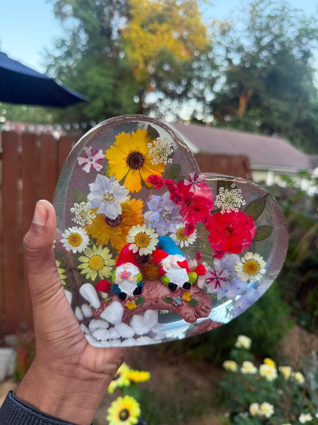 Pressed flower and gnome resin heart held outdoors, main product photo